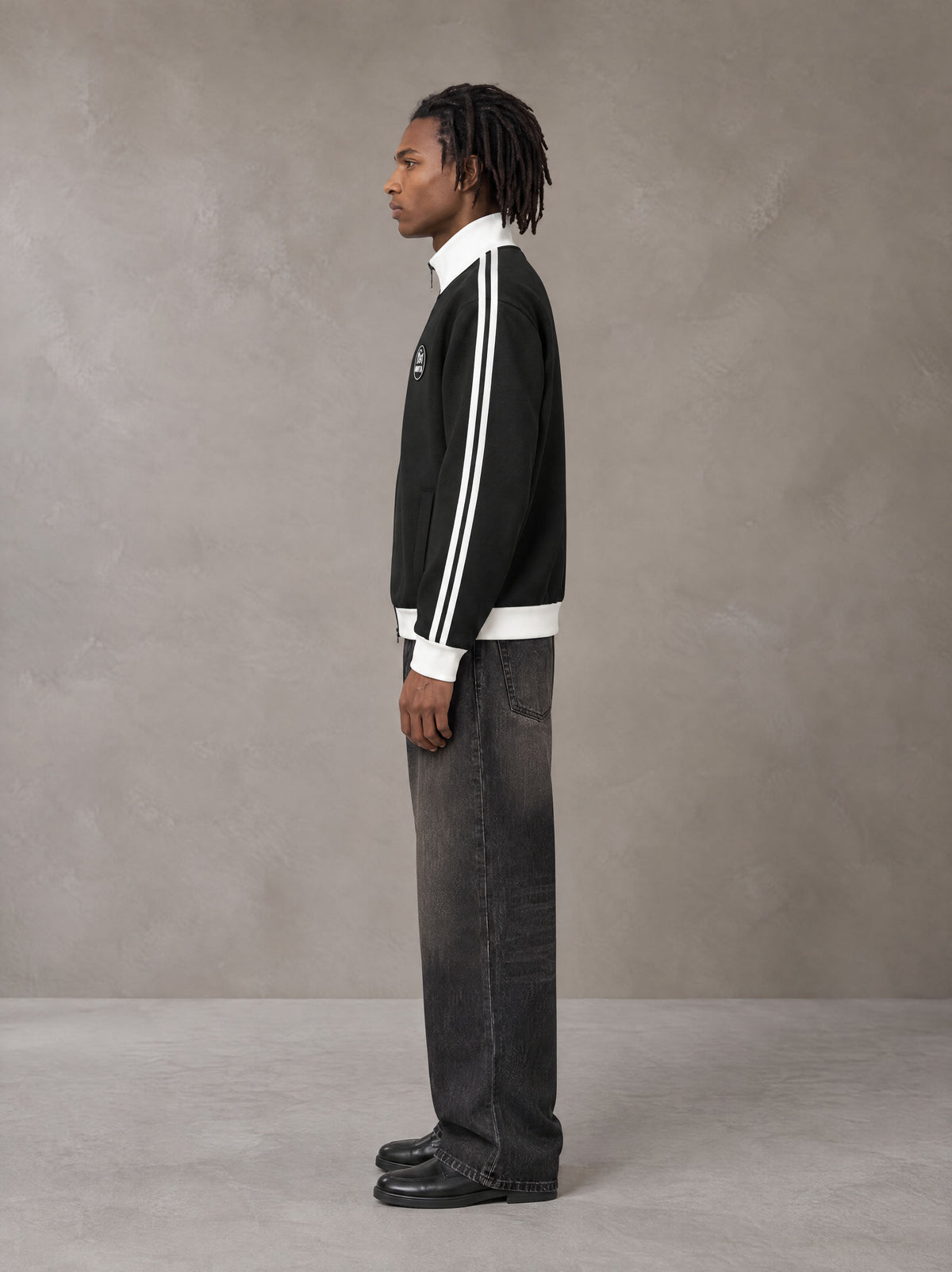 Model wearing the SM Insignia Contrast Trim Jacket in Midnight Black, side profile.
