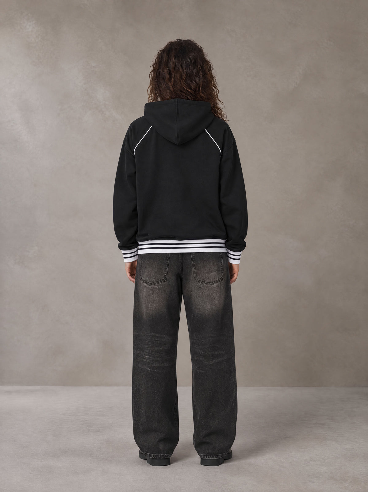Model wearing the SM Insignia Hoodie in Midnight Black, rear view.