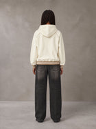 Model wearing the SM Insignia Hoodie in Soft Beige, rear view.