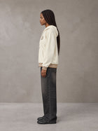 Model wearing the SM Insignia Hoodie in Soft Beige, side profile.