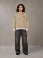 Model wearing the SM Insignia Hoodie in Oatmeal Cookie, front view.