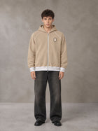 Model wearing the SM Insignia Hoodie in Oatmeal Cookie, front view.