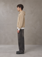 Model wearing the SM Insignia Hoodie in Oatmeal Cookie, side profile.
