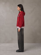 Model wearing the SM Insignia Hoodie in Carmine, side profile.