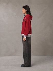 Model wearing the SM Insignia Hoodie in Carmine, side profile.