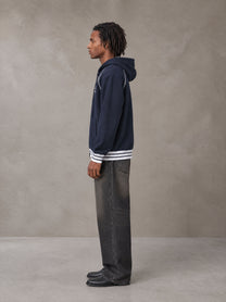 Model wearing the SM Insignia Hoodie in Oxford Navy, side profile.