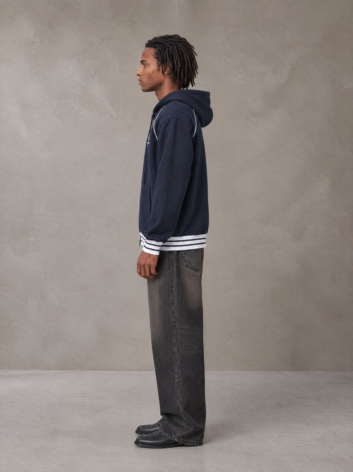 Model wearing the SM Insignia Hoodie in Oxford Navy, side profile.