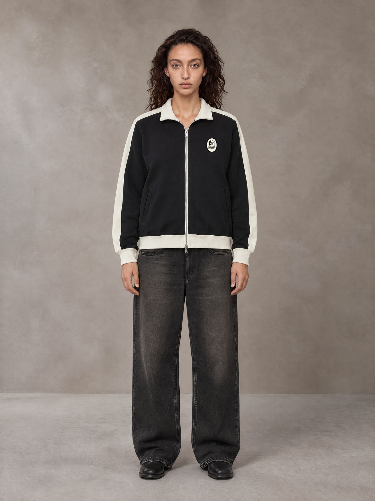 Model wearing the SM Insignia Jacket in Midnight Black, front view.