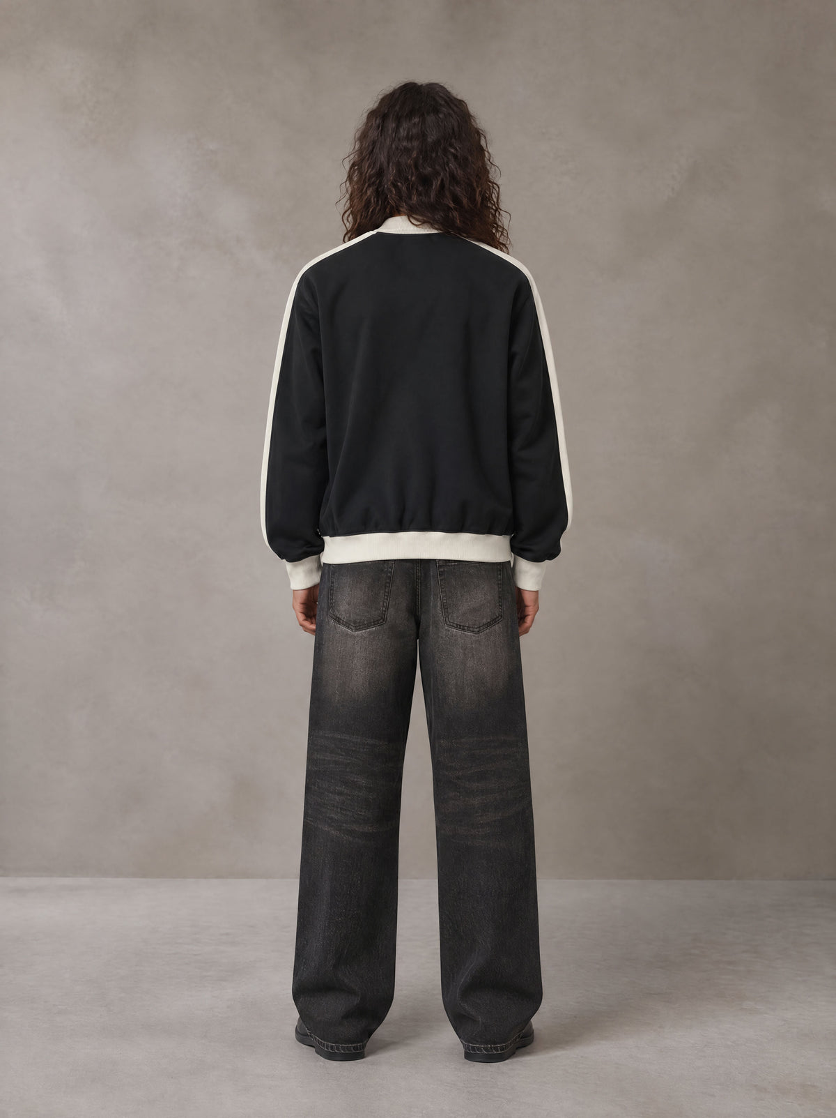 Model wearing the SM Insignia Jacket in Midnight Black, rear view.