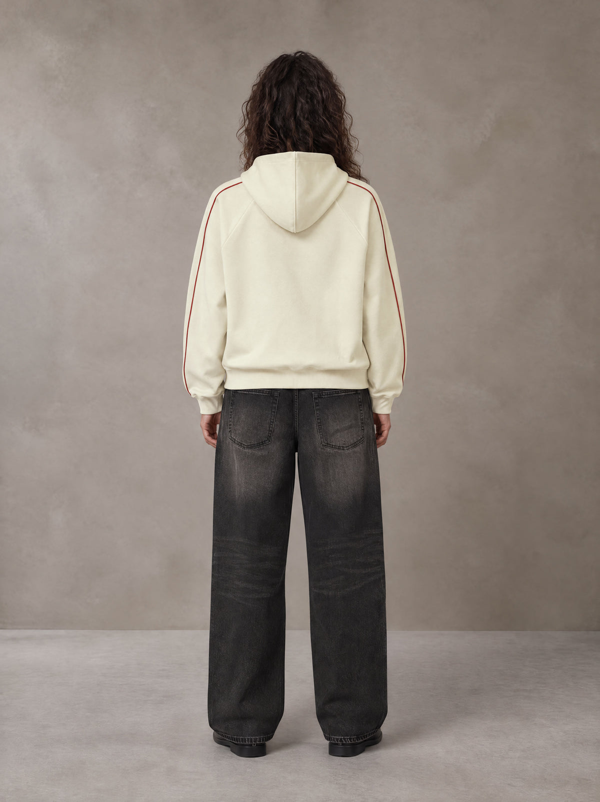 Model wearing the SM Insignia Parallel Hoodie in Classic Cream, rear view.