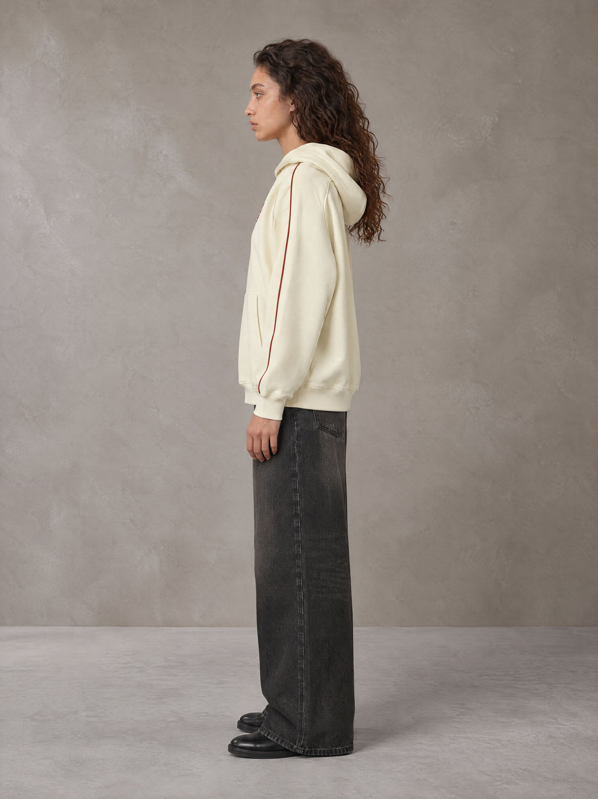 Model wearing the SM Insignia Parallel Hoodie in Classic Cream, side profile.