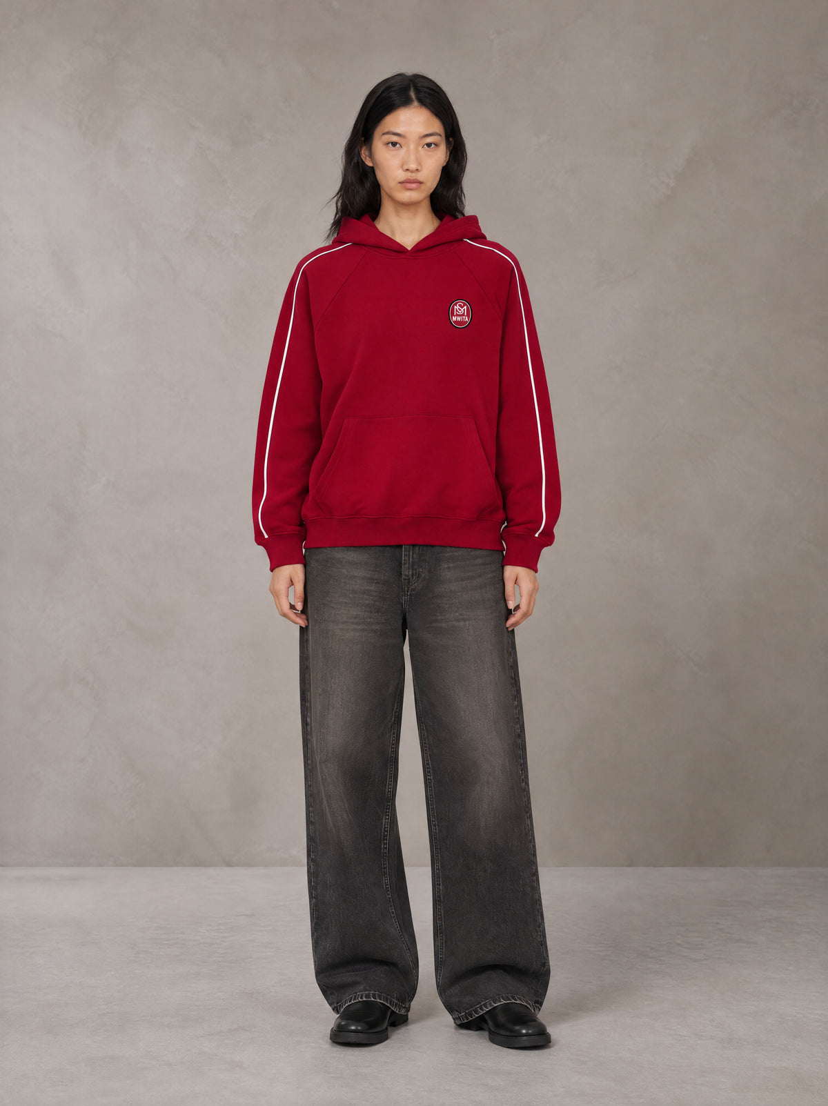 Model wearing the SM Insignia Parallel Hoodie in Carmine, front view.