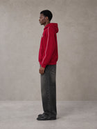 Model wearing the SM Insignia Parallel Hoodie in Carmine, side profile.