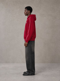 Model wearing the SM Insignia Parallel Hoodie in Carmine, side profile.