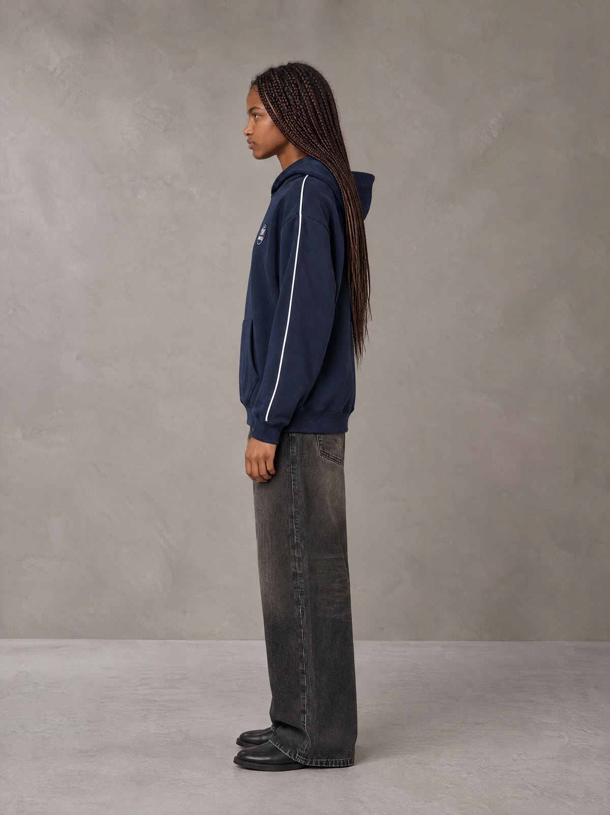 Model wearing the SM Insignia Parallel Hoodie in Oxford Navy, side profile.