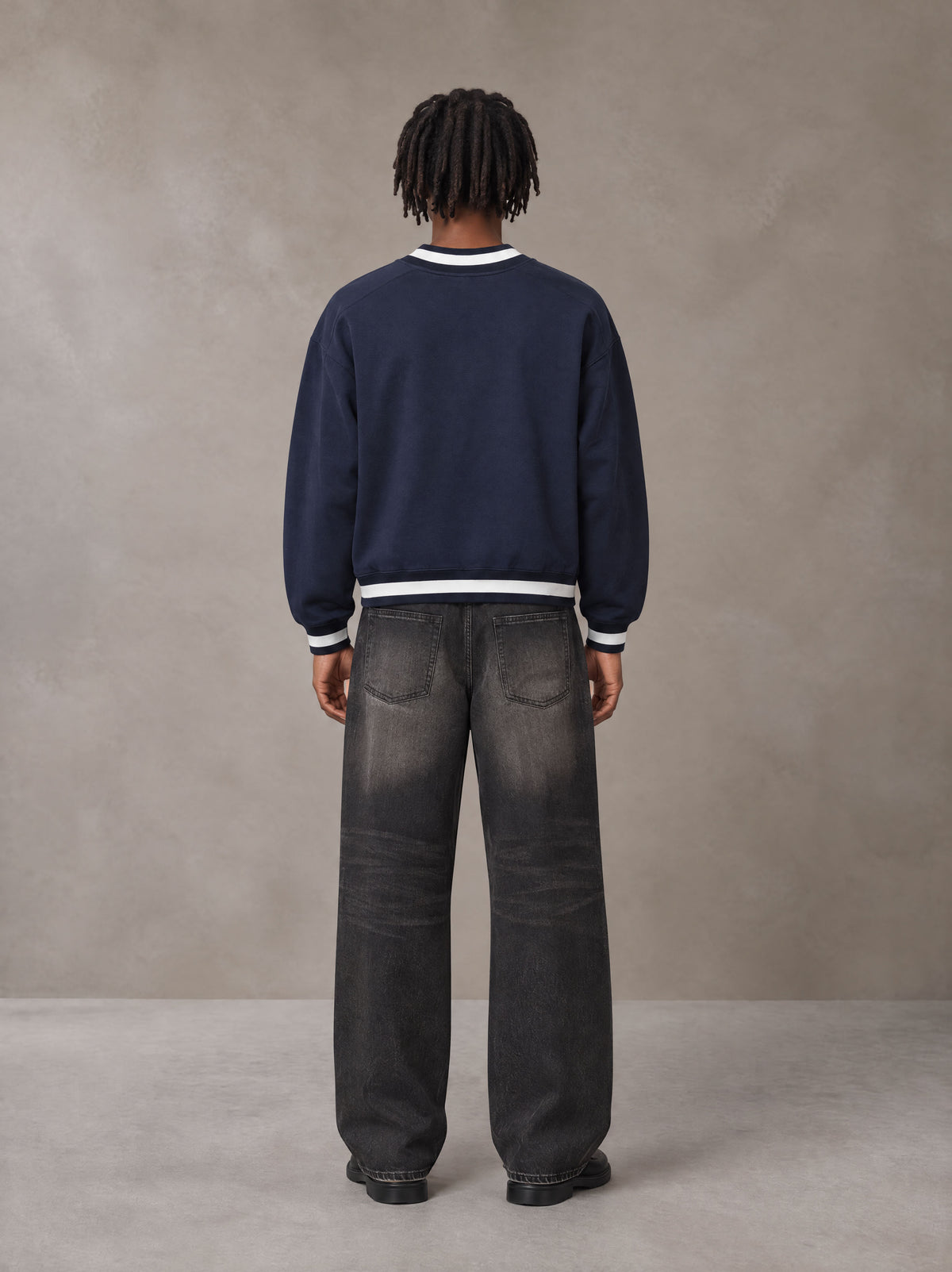 Model wearing the SM Insignia Sweatshirt in Oxford Navy, rear view.