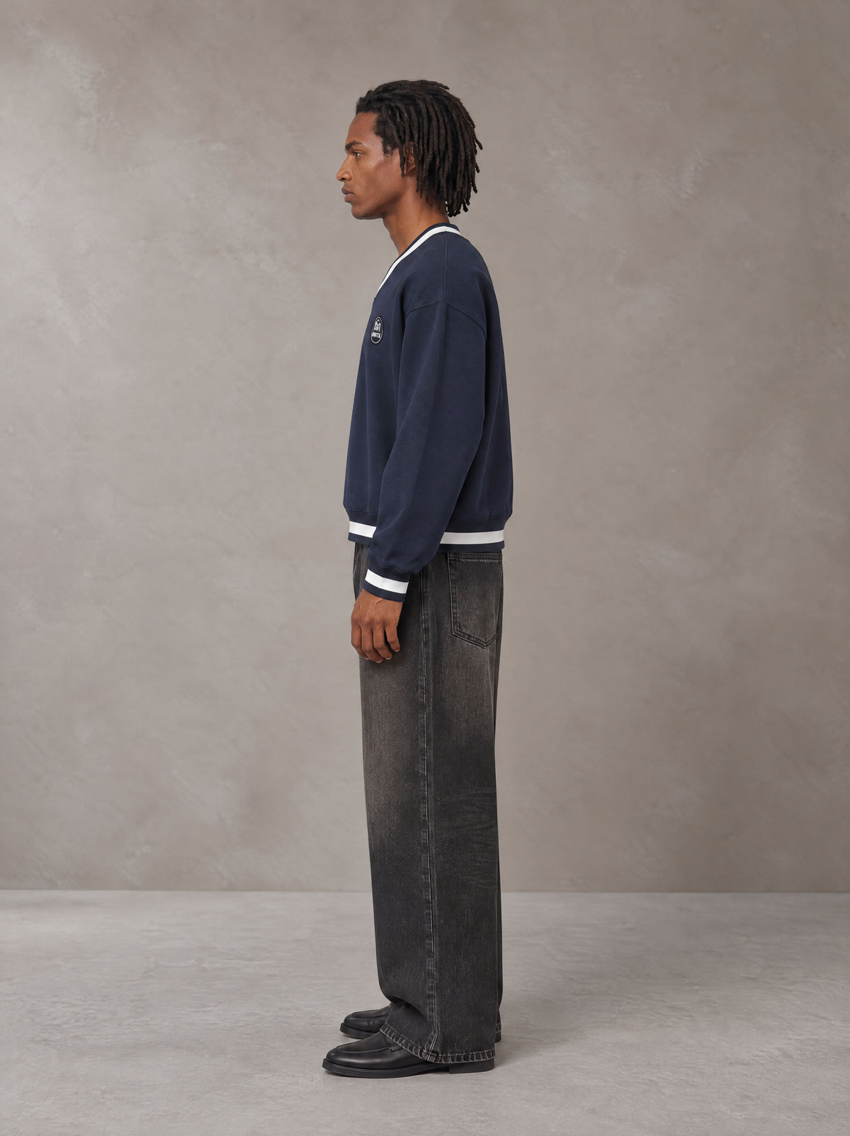 Model wearing the SM Insignia Sweatshirt in Oxford Navy, side profile.