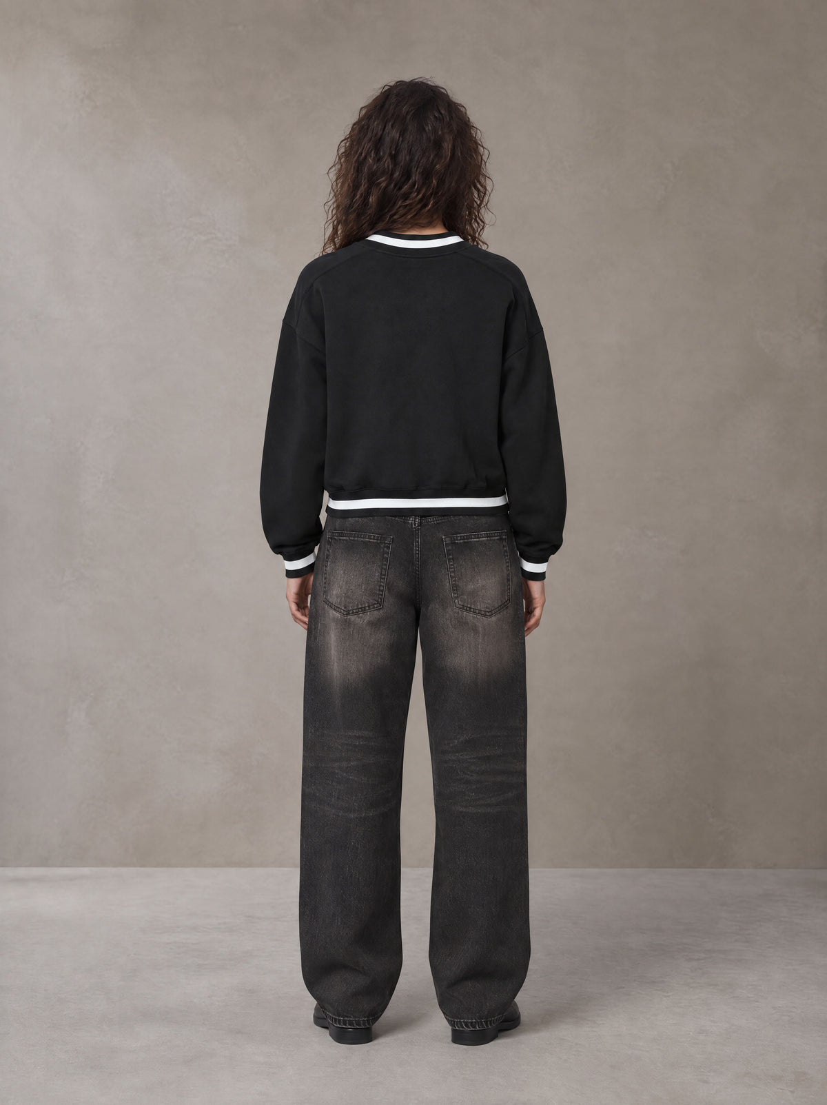 Model wearing the SM Insignia Sweatshirt in Midnight Black, rear view.