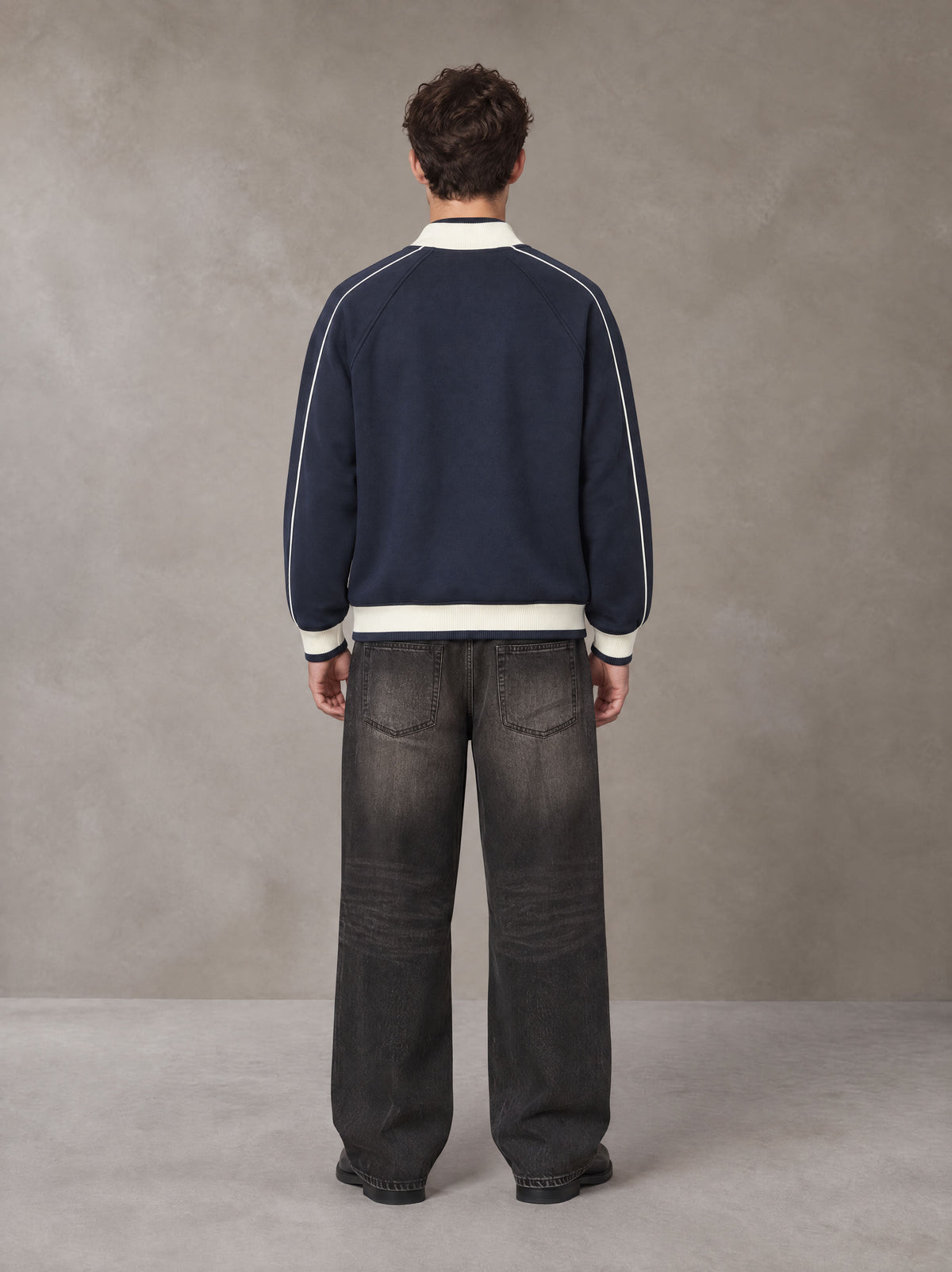 Model wearing the SM Insignia Trim Track Jacket in Oxford Navy, rear view.