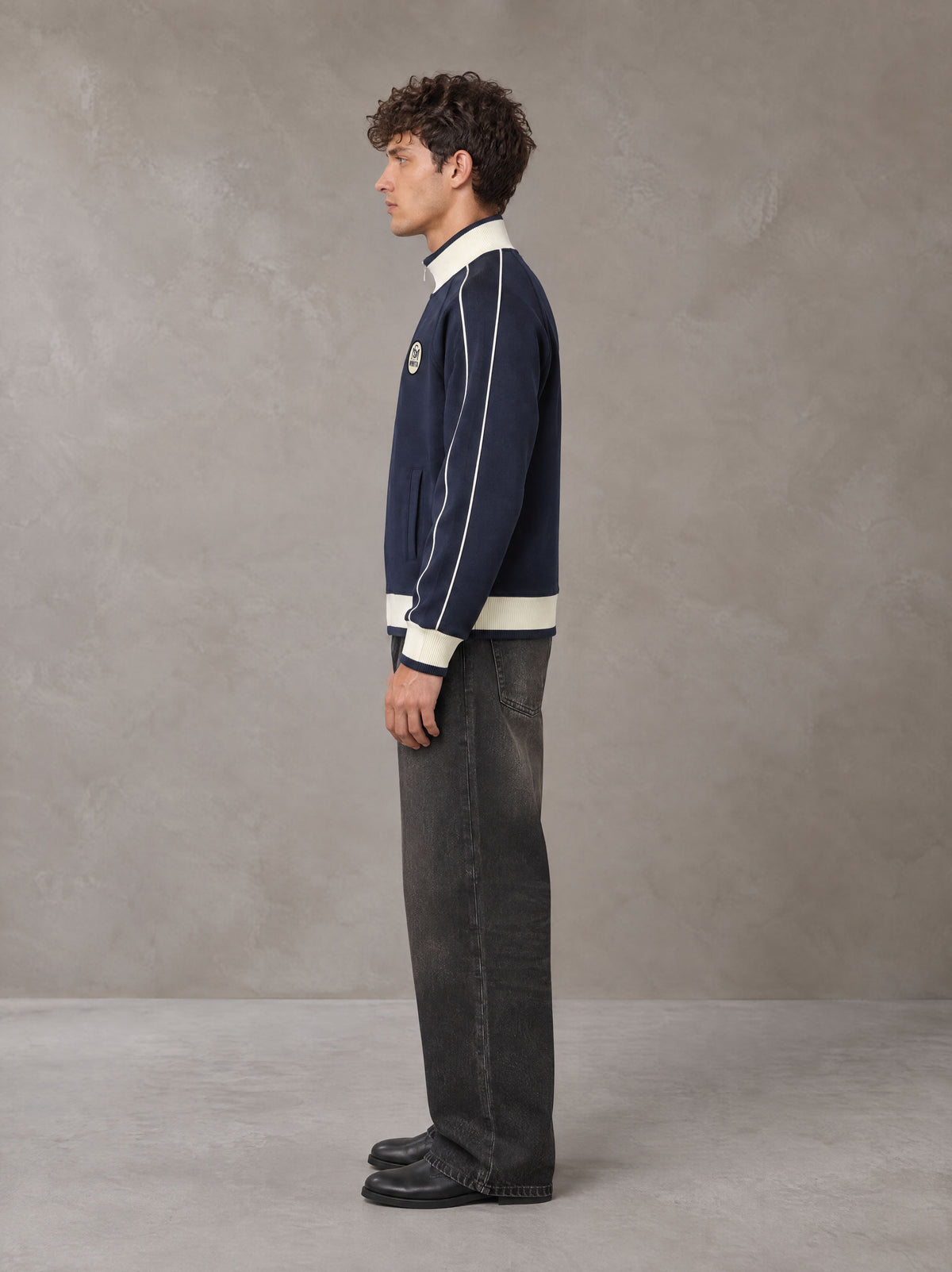 Model wearing the SM Insignia Trim Track Jacket in Oxford Navy, side profile.