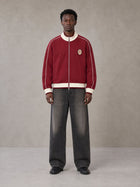 Model wearing the SM Insignia Trim Track Jacket in Carmine, front view.