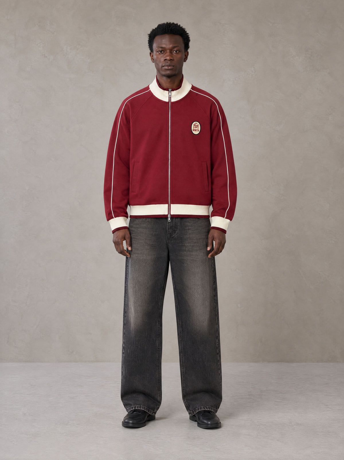 Model wearing the SM Insignia Trim Track Jacket in Carmine, front view.