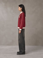 Model wearing the SM Insignia Trim Track Jacket in Carmine, side profile.