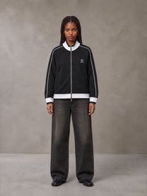 Model wearing the SM Insignia Trim Track Jacket in Midnight Black, front view.