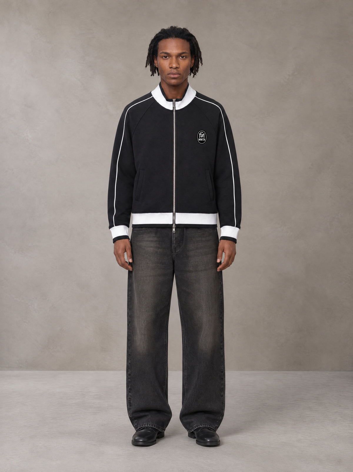 Model wearing the SM Insignia Trim Track Jacket in Midnight Black, front view.