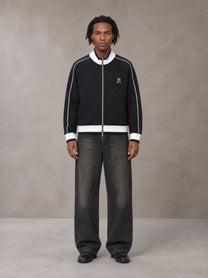 Model wearing the SM Insignia Trim Track Jacket in Midnight Black, front view.