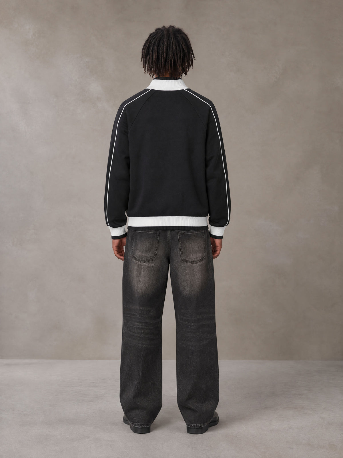 Model wearing the SM Insignia Trim Track Jacket in Midnight Black, rear view.