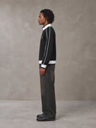 Model wearing the SM Insignia Trim Track Jacket in Midnight Black, side profile.