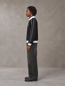 Model wearing the SM Insignia Trim Track Jacket in Midnight Black, side profile.