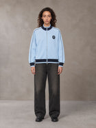 Model wearing the SM Insignia Trim Track Jacket in Sky Tint, front view.