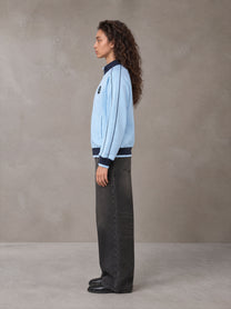 Model wearing the SM Insignia Trim Track Jacket in Sky Tint, side profile.