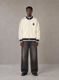 Model wearing the SM Insignia Trim Track Jacket in Classic Cream, front view.