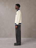 Model wearing the SM Insignia Trim Track Jacket in Classic Cream, side profile.