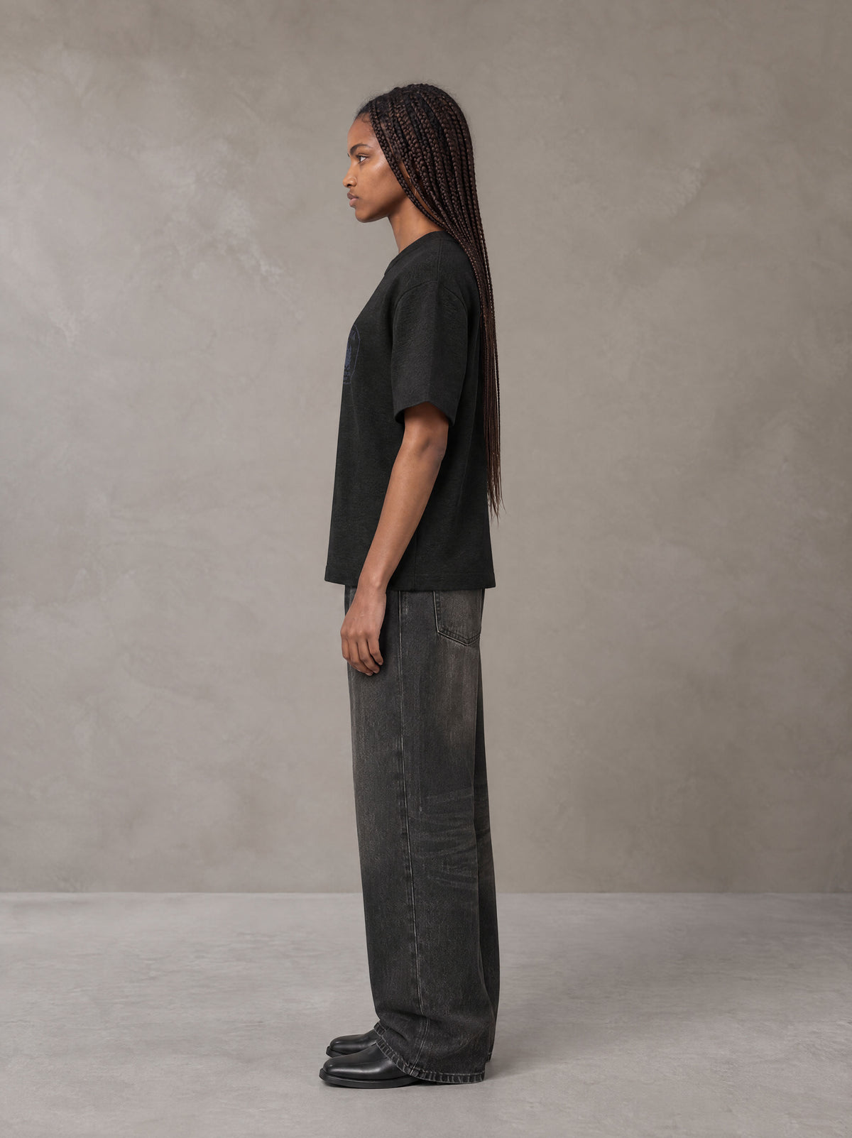 Model wearing the SM Jacquard Knitted Royal Emblem Knitted T-shirt in Midnight Black, side profile.