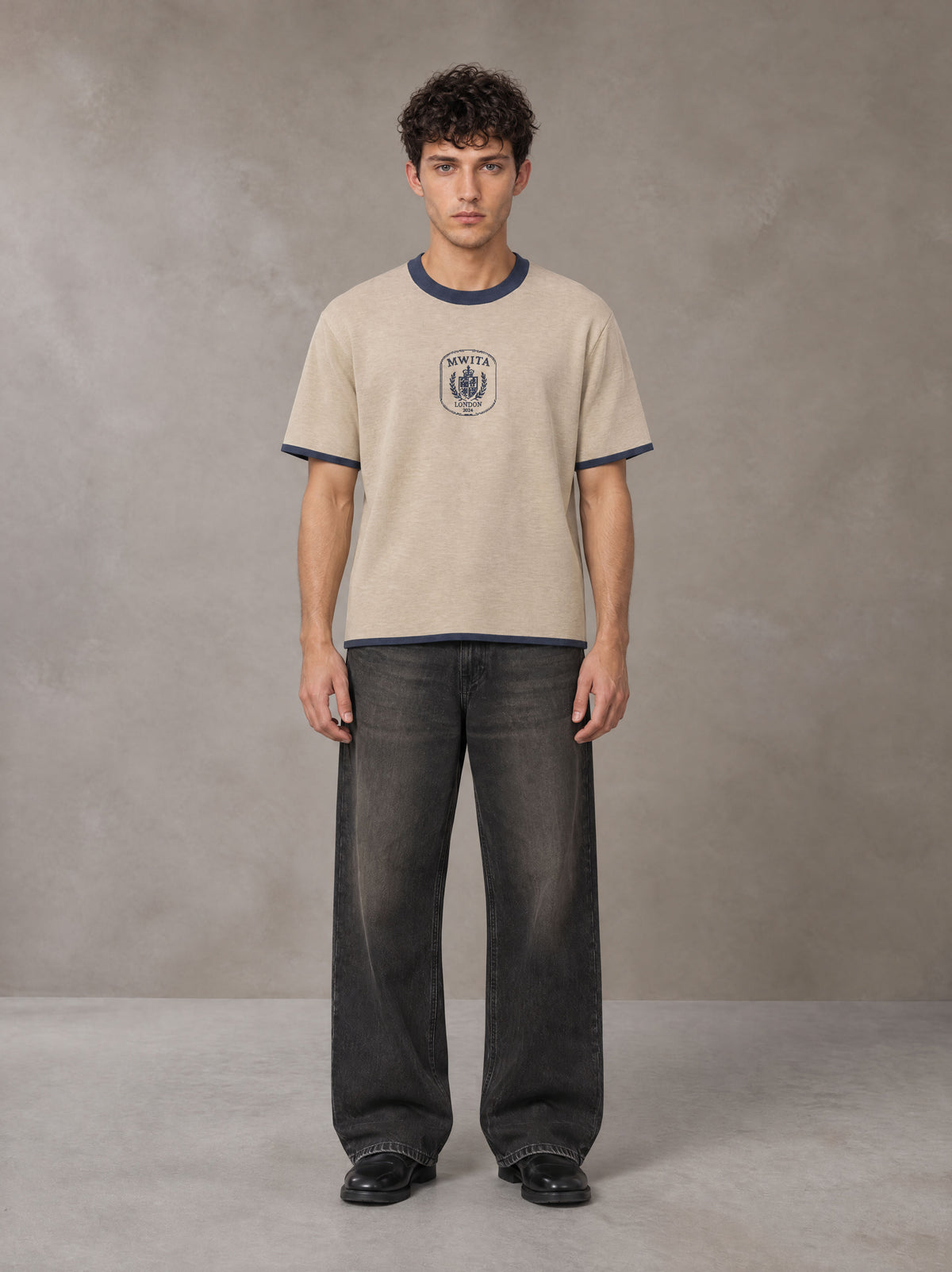 Model wearing the SM Jacquard Knitted Royal Emblem Knitted T-shirt in Oatmeal Cookie, front view.