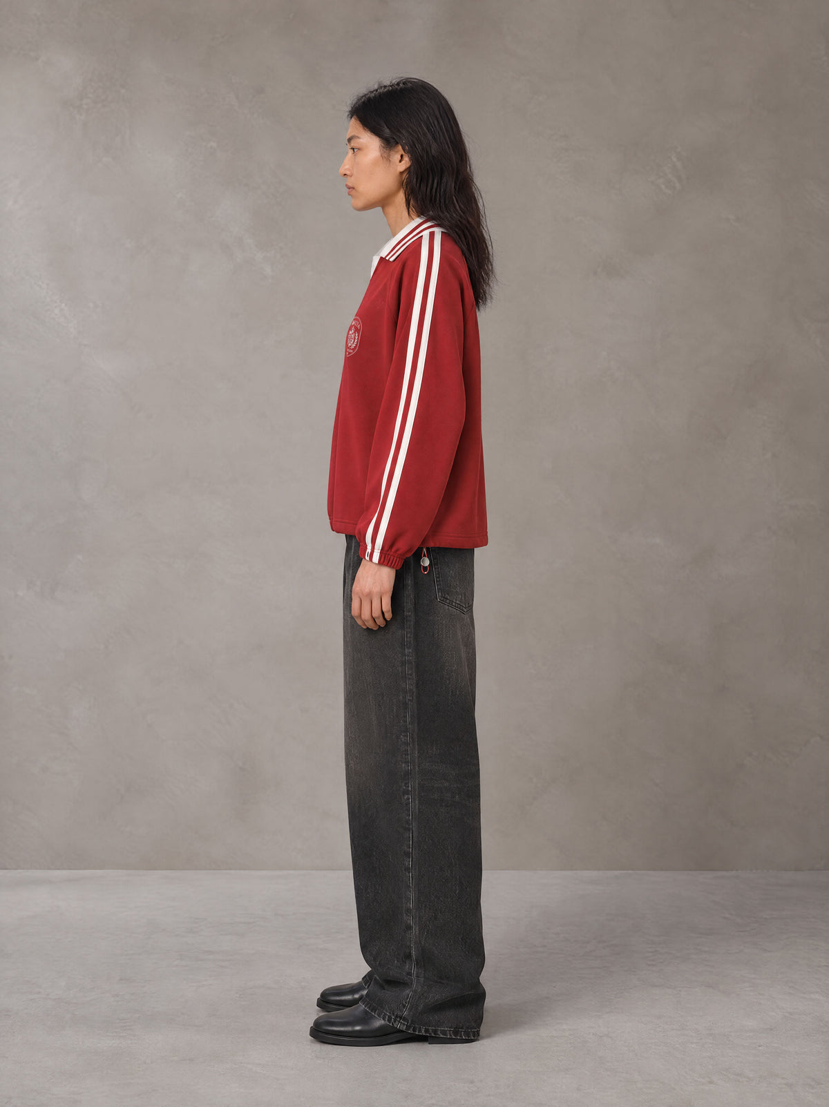 Model wearing the SM Royal Emblem Panel Sweatshirt in Crimson, side profile.