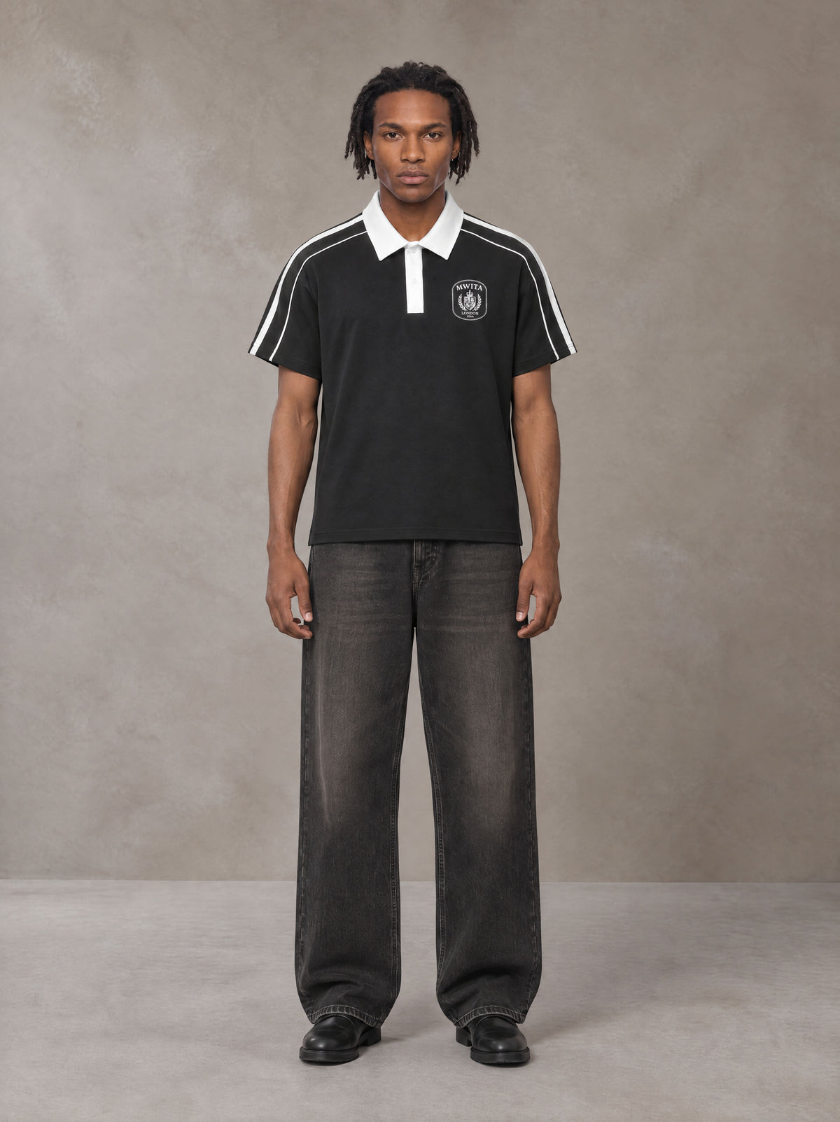 Model wearing the SM Royal Emblem Polo T-shirt in Midnight Black, front view.