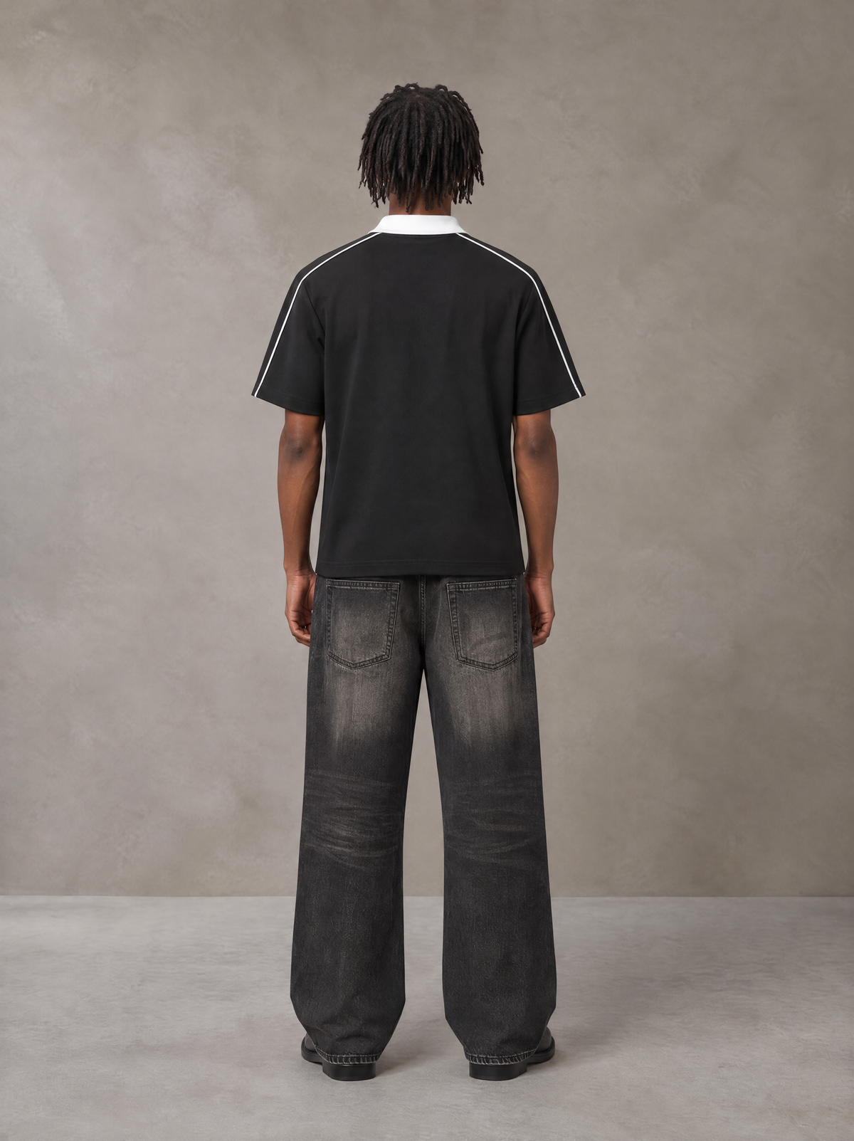 Model wearing the SM Royal Emblem Polo T-shirt in Midnight Black, rear view.