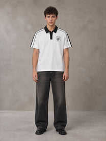 Model wearing the SM Royal Emblem Polo T-shirt in Lucent White, front view.