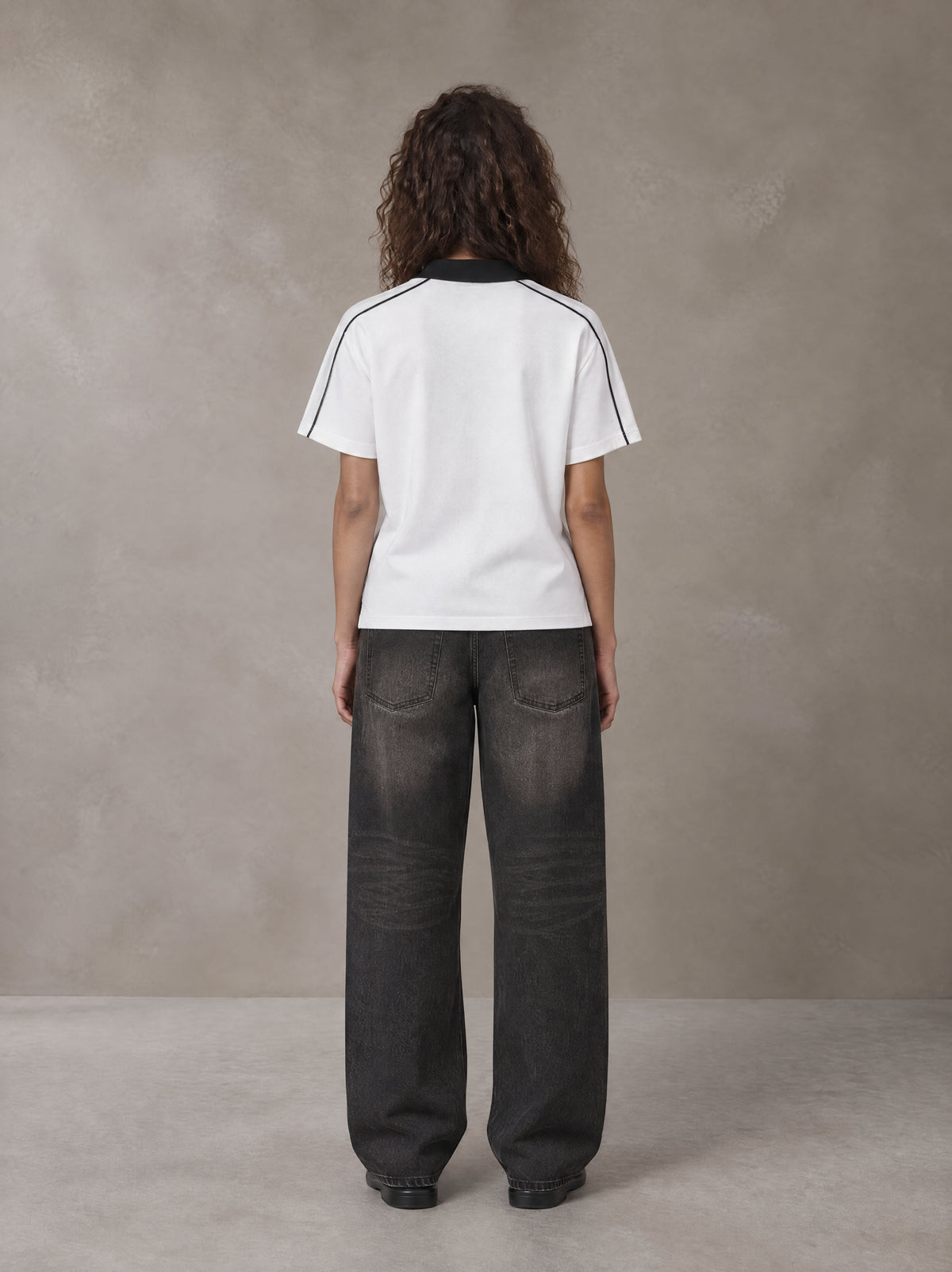 Model wearing the SM Royal Emblem Polo T-shirt in Lucent White, rear view.