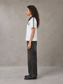 Model wearing the SM Royal Emblem Polo T-shirt in Lucent White, side profile.