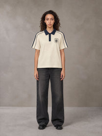 Model wearing the SM Royal Emblem Polo T-shirt in Soft Beige, front view.