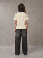 Model wearing the SM Royal Emblem Polo T-shirt in Soft Beige, rear view.