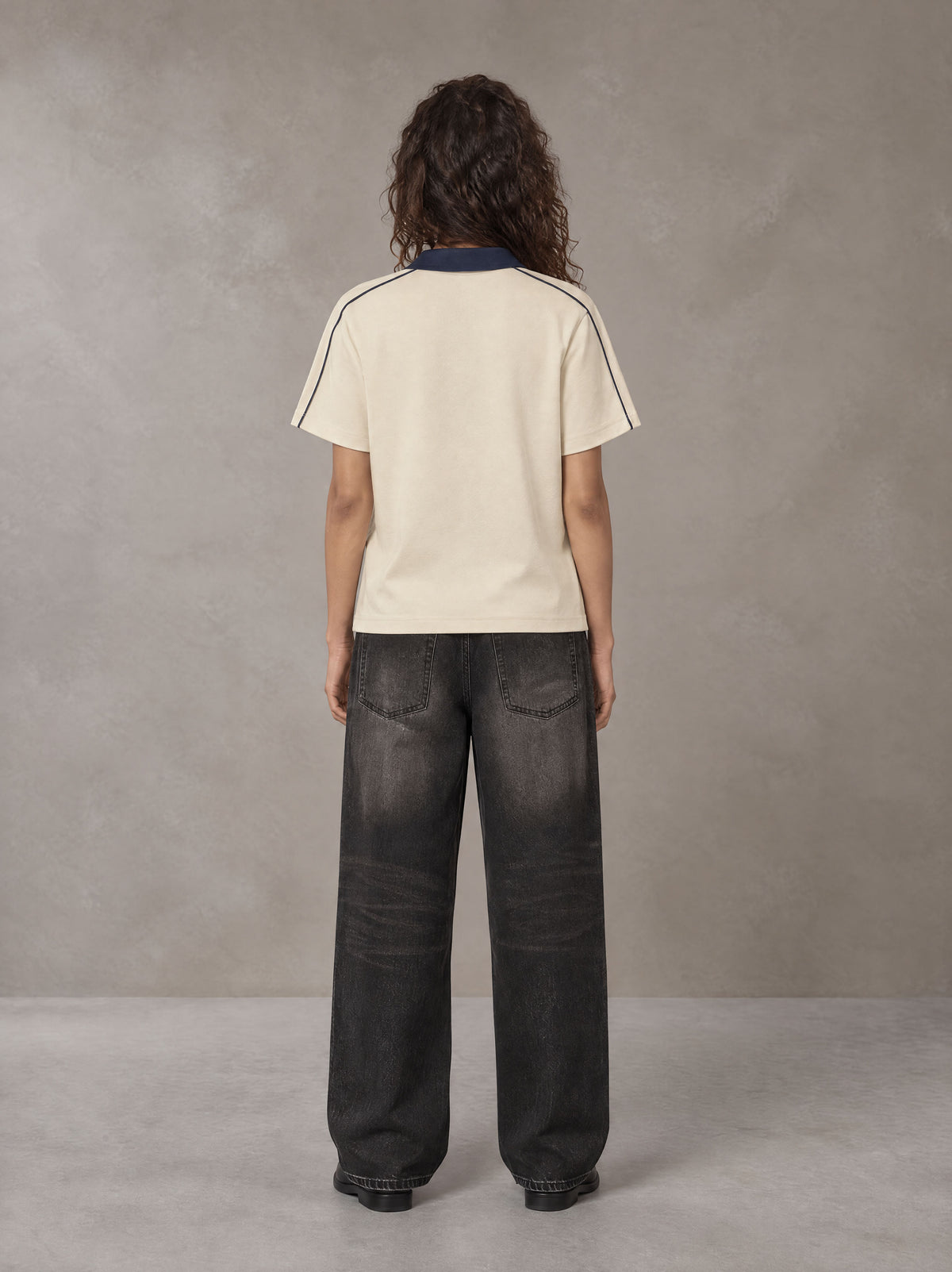 Model wearing the SM Royal Emblem Polo T-shirt in Soft Beige, rear view.