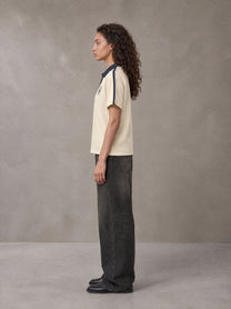 Model wearing the SM Royal Emblem Polo T-shirt in Soft Beige, side profile.
