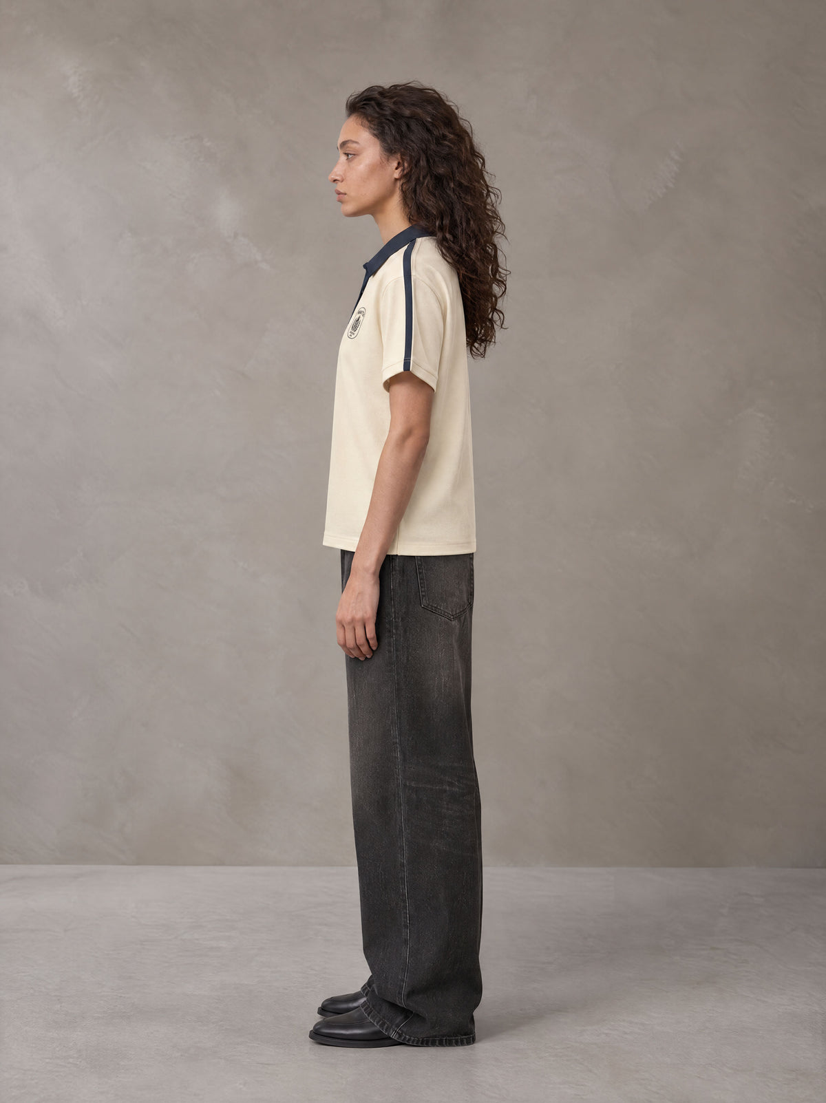Model wearing the SM Royal Emblem Polo T-shirt in Soft Beige, side profile.